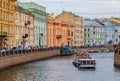 Waterfront buildings on the banks of river Neva and tourist boats on the water in Saint Petersburg