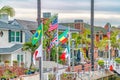 Waterfront houses colorful flags and palm trees along a canal under cloudy sky Royalty Free Stock Photo