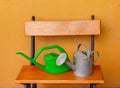 A watering can of aluminium and a plastic one laid on wooden be Royalty Free Stock Photo