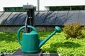 Watering can green and made of plastic on the cemetery put at disposal of the visitors to water the grave and maintain them