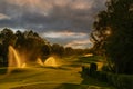 Watering grass in golf course at sunset with dramatic sky Royalty Free Stock Photo