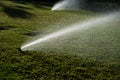 Watering grass. Sprinklers watering grass, green lawn in garden. Automatic sprinkler irrigation system working in a Royalty Free Stock Photo