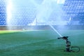 Watering green grass in stadium, Restoring field in morning after football match