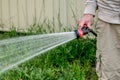 Watering the lawn with the garden hose. Hands holding water hose