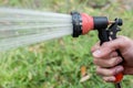 Watering the lawn with the garden hose. Hands holding water hose
