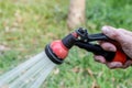 Watering the lawn with the garden hose. Hands holding water hose