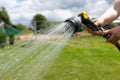 watering the lawn on a hot day with a garden hose with a sprayer Royalty Free Stock Photo