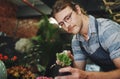 Watering plants is so therapeutic. a handsome young florist watering flowers inside his plant nursery. Royalty Free Stock Photo