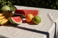 Watermelon, bananas, orange, apple and mint leaves on the table in the sun. Tropical fruits. Generative ai
