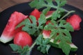 Watermelon cut into pieces on a black plate close-up with leaves. Royalty Free Stock Photo