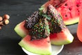 Watermelon in dark chocolate and multicolored topping.