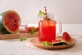 Watermelon drink in glass with slices of watermelon on whitebackground