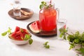 Watermelon drink in glass with slices of watermelon on whitebackground