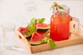 Watermelon drink in glass with slices of watermelon on whitebackground