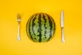 Watermelon with a fork and a knife next to it on a yellow background Royalty Free Stock Photo