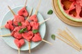 Watermelon heart popsicles on blue plate and wooden sticks and piece of watermelon on gray stone background.