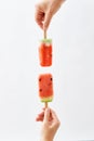 Watermelon ice lolly. Female hands holding juicy slices of watermelon on a stick on a white background with space for