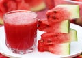 Watermelon juice with sliced fruit on white plate