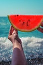 Watermelon, juicy, red slice in the hands of a woman against the background of the ocean Royalty Free Stock Photo