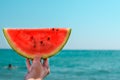 Watermelon, juicy, red slice in the hands of woman against the background of the ocean. Royalty Free Stock Photo