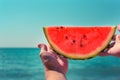 Watermelon, juicy, red slice in the hands of a woman against the background of the ocean Royalty Free Stock Photo