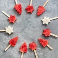Watermelon and melon slice popsicles on gray background. Round frame of popsicles in the shape of a Christmas tree and a star.