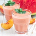 Watermelon, peach, mint and coconut milk smoothie in a glass on white wooden background, square format Royalty Free Stock Photo