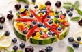 Watermelon pizza with addition of fersh blueberries, strawberries, natural yogurt and edible flowers