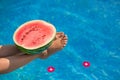 Watermelon in pool on woman slim legs in summer holiday time. Instagram tropical beach luxury lifestyle. Woman relaxing, Royalty Free Stock Photo