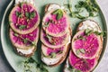 Watermelon radish toast with cream cheese and micro-green peas in a green ceramic plate