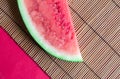 Watermelon slice on reed tablemat with red background close up Royalty Free Stock Photo
