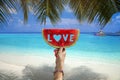 Watermelon slice with text love, woman hands holding it against blue sky and Indian ocean. Royalty Free Stock Photo