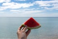 Watermelon slice in woman hand over sea Royalty Free Stock Photo