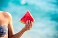 Watermelon slice in woman hand over sea - POV. Summer beach concept. Tropical fruit diet. Royalty Free Stock Photo