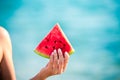 Watermelon slice in woman hand over sea - POV. Summer beach concept. Tropical fruit diet. Royalty Free Stock Photo