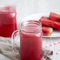 Watermelon smoothie in glass jars with fresh slices of water melon over white wooden sbackground, side view. Close-up Royalty Free Stock Photo