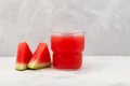 Watermelon smoothie or watermelon juice in clear glass on grey background. Near lie juicy slices with red pulp. Jus semangka. Royalty Free Stock Photo