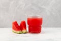 Watermelon smoothie or watermelon juice in clear glass on grey background. Near lie juicy slices with red pulp. Jus semangka. Royalty Free Stock Photo