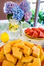 Watermelon triangle slices, yellow orange Mellon slices and lemonade on a table. A vase with flowers in the background Royalty Free Stock Photo