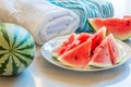 watermelon wedges on a plate beside beach towels