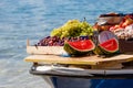 Watermelons, green and purple grapes, peaches in a boat on a sea background