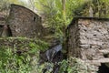 Watermill in the middle of a forest. Rustic building made of rock. Small waterfal