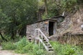 Watermill in the middle of a forest. Rustic building made of rock with wooden stairs