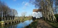 Watermill and Mill stream at Lode in Cambridgeshire with trees and blue sky. Royalty Free Stock Photo