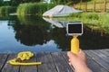 Waterproof action camera with a yellow float in a man`s hand. Background mask for snorkeling, diving on a wooden pier with a boat