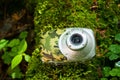 Waterproof compact camera covered with water drops lying on the forest floor