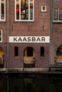Waters edge view of restaurant bar sign Kaasbar, at an old ancient red brick building by the canal in Utrecht.