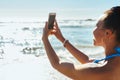 The waters never looked more inviting. a young woman using a mobile phone to take photographs at the beach. Royalty Free Stock Photo