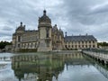 Waterside view of the Musee Conde building under the cloudy sky