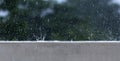 Watersplash by rain drops on a wall against a tree background